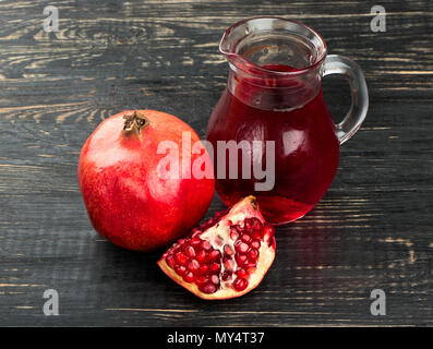 Granatapfelsaft in Behältnissen aus Glas mit Obst auf den Tisch Stockfoto