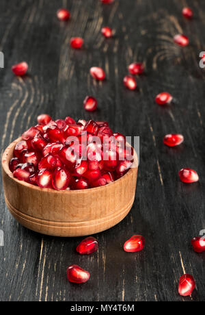 Frischer Granatapfel Samen in eine Schüssel geben und auf den Tisch verstreut Stockfoto