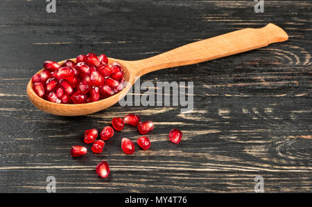 Granatapfel Samen in einem Löffel aus Holz auf einem dunklen Tabelle Stockfoto