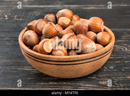 Volle Schüssel frische Haselnüsse in der Schale auf dem hölzernen Hintergrund Stockfoto