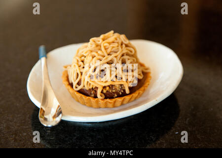 Mont Blanc Kuchen auf einem weißen Teller mit der Gabel auf einen dunklen Tisch Stockfoto