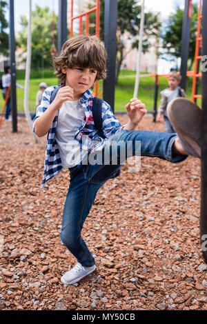 Ernst kleiner Junge Boxsack schlagen auf dem Spielplatz Stockfoto