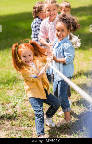 Adorable glücklich multiethnischen Kinder spielen Tauziehen in Park Stockfoto