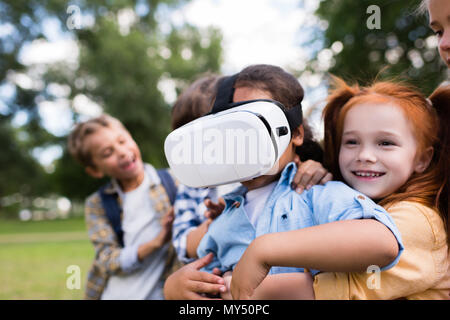 Happy African American Girl mit Virtual reality Headset beim Spielen mit Freunden im Park Stockfoto