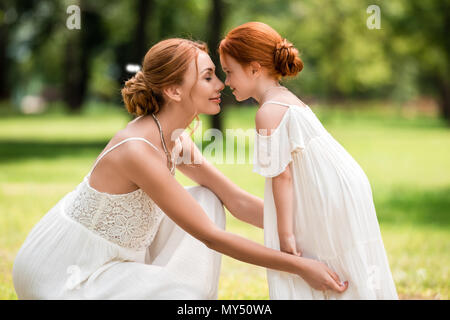 Seitenansicht Porträt der schönen Happy rothaarigen Mutter und Tochter Flächen berühren im Park Stockfoto