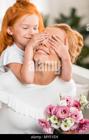 Porträt der kleinen Tochter, die Augen der jungen Mutter mit Blumen, glücklichen Muttertag Konzept Stockfoto