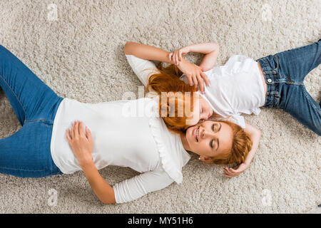 Ansicht von oben der lächelnden Mutter und Tochter gemeinsam auf dem Boden liegend zu Hause Stockfoto