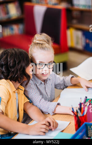 Schöne Mädchen tratschen in Bibliothek Stockfoto