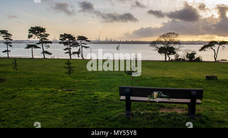 Den Sonnenuntergang Silhouetten der industriellen Türme von Fawley Ölraffinerie und Bäume im netley Country Park an den Ufern des Southampton Wasser. Stockfoto