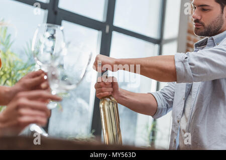 Junger Mann öffnen Weinflasche für Datum mit Freundin zu Hause Stockfoto