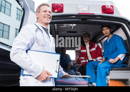 Lächelnd Sanitäter arbeiten team mit Krankenwagen Stockfoto