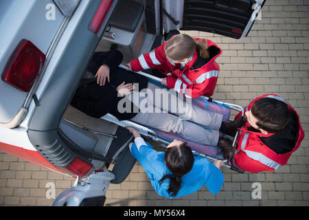 Blick von oben auf die Sanitäter Team bewegte Mann auf krankenwagenbahre in Auto Stockfoto