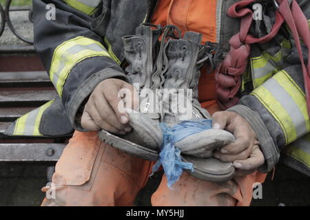 San Juan Alotenango, Guatemala. 05 Juni 2018, Guatemala, San Juan Alotenango: Mitglied der Feuerwehr hält seine Schuhe bei den Rettungsarbeiten nach dem Vulkanausbruch des Volcan De Fuego (Feuer Vulkan). Nach der Eruption, rescue Teams waren mit schrecklichen Anblick konfrontiert. In einigen Häusern, die von den Klippen der Vulkan, entdeckten sie ganze Familien, die in der Katastrophe gestorben. Mindestens 70 Menschen wurden bei dem Vulkanausbruch ums Leben. Foto: Alejandro Balan/dpa Quelle: dpa Picture alliance/Alamy leben Nachrichten Stockfoto