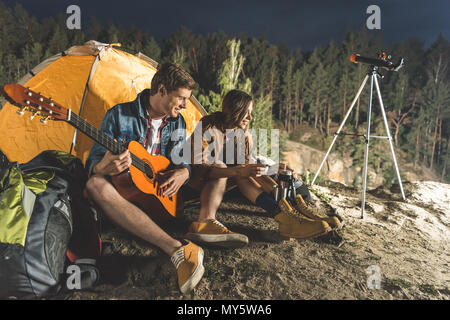 Junger Mann mit Gitarre für schöne glückliche Freundin in Wandern Reise Stockfoto