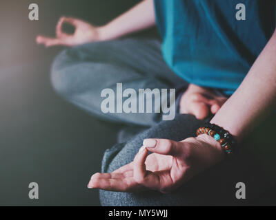 Nahaufnahme der Frau die Hände mit Armbänder der Meditation im Lotussitz im Innenbereich. Gyan Mudra. Yoga, Religion Konzept. Stockfoto