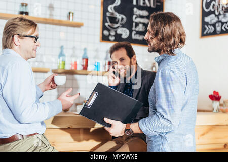 Stattlich im mittleren Alter Unternehmer diskutieren Projekt beim Trinken Kaffee im Cafe Stockfoto