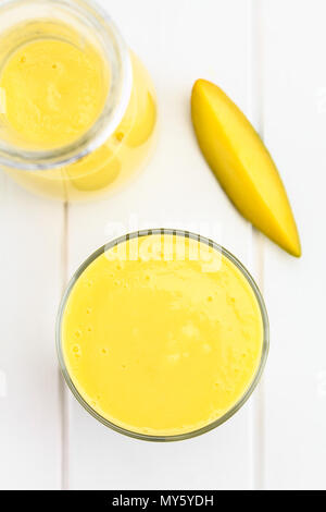 Erfrischende Mango und Joghurt Smoothie in Glas, Overhead, fotografiert auf weißem Holz (selektive Fokus, Fokus auf der Oberseite des Getränk) Stockfoto