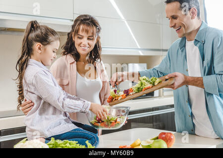 Glücklich lächelnde Familie Salat zusammen, in der Küche Stockfoto