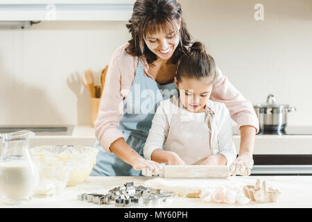Glückliche Mutter mit Tochter rollt Teig durch Rolling Pin Küche Stockfoto
