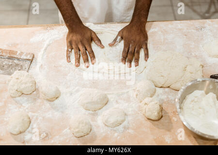 7/8 shot der afrikanischen amerikanischen Baker kneten den Teig für Gebäck auf unordentliche Tabelle Stockfoto