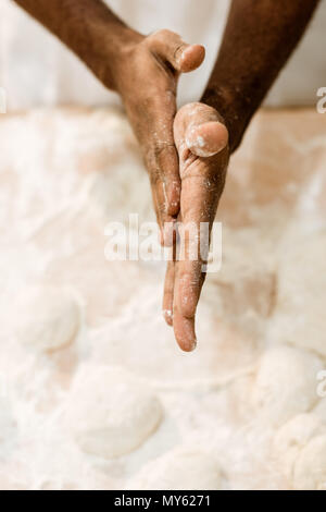7/8 shot der afrikanischen amerikanischen Baker Zubereitung Teig für Gebäck und die Hände in Mehl Stockfoto