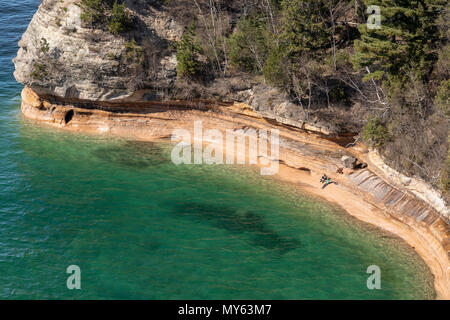 Munising, Michigan - ein Mann und eine Frau, die am Ufer des Lake Superior an der Basis der Bergleute Castle Rock Formation in die dargestellten Felsen nationalen Lakesho Stockfoto