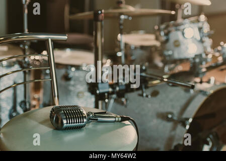 Vintage Mikrofon auf Stuhl vor Drum Set liegen Stockfoto