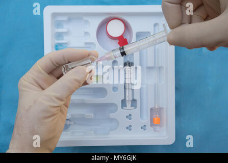 Eine rechtshändige Anästhesisten Aberkennung Lidocain oder Novocaine in eine Nadel in der Vorbereitung für die Verwaltung einer spinalen Anästhesie. Stockfoto