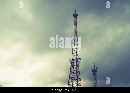 Radio Telekommunikation Turm, Handy Turm und alte Rohre, die Gewitterwolken. Dramatische Landschaft mit Cloud storm Cloud und Metall Fernsehturm Stockfoto