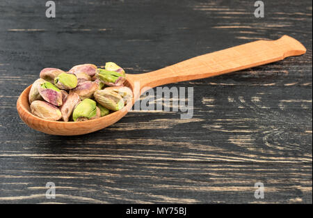 Pistazien ohne Schale in einem Löffel auf einer hölzernen Hintergrund Stockfoto