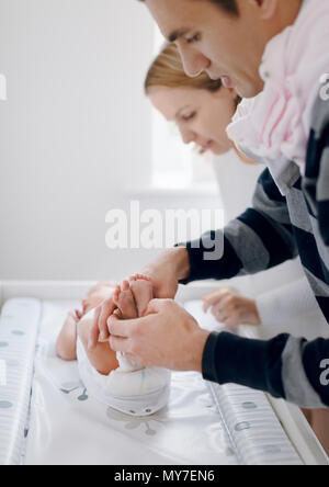 Mutter und Vater dressing neugeborenes Baby Stockfoto