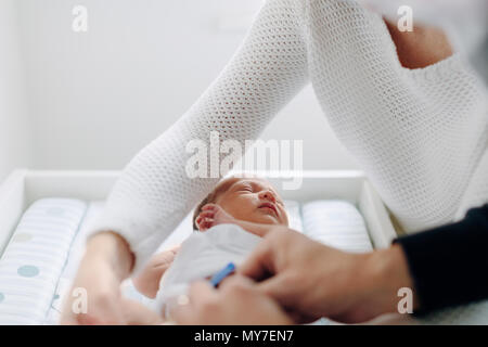 Mutter und Vater dressing neugeborenes Baby Stockfoto