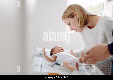 Mutter und Vater dressing neugeborenes Baby Stockfoto