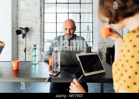 Kollegen am Schreibtisch mit Laptop und digitale Tablet Stockfoto