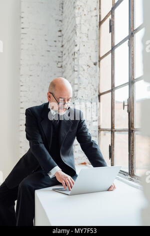 Geschäftsmann, sitzen auf der Fensterbank mit laptop Stockfoto