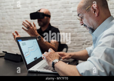 Mann mit Laptop, Test virtual reality Headset Stockfoto