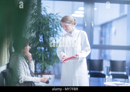 Radiologen, digitale Tablet, sprechen mit reife Frau im Wartebereich des Krankenhauses Stockfoto