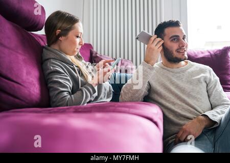 Paar entspannt auf einem Sofa mit Smartphones Stockfoto