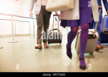 Geschäftsmänner und Frauen am Flughafen, Koffer mit Rädern ziehen, niedrige Abschnitt Stockfoto