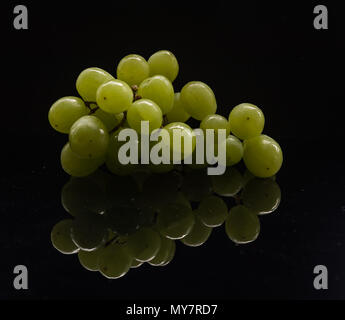 Ein Bündel aus weißen Trauben mit einer Reflexion in einem low-key-Format Stockfoto