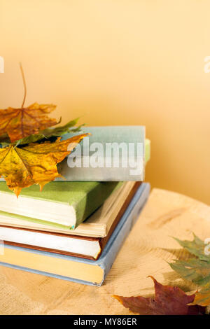 Stapel von Büchern mit Herbstlaub auf Holz geschnitten. Zurück zum Konzept der Schule. Stockfoto