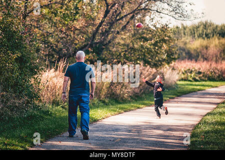 Vater und Sohn das Spiel mit dem Ball auf Weg Stockfoto