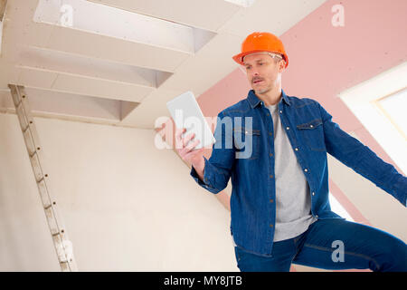 Portrait von im mittleren Alter Bauarbeiter mit digitalen tablet, während auf der Leiter auf der Baustelle stehen. Stockfoto