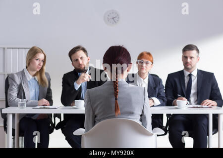 Frau beim Vorstellungsgespräch und vier elegante Mitglieder der Geschäftsleitung Stockfoto