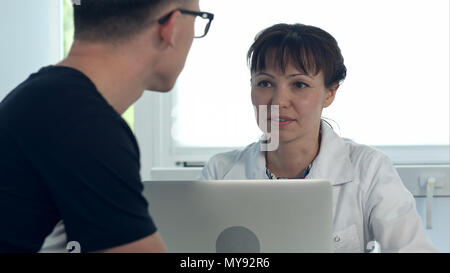 Weibliche Arzt Diagnose diskutiert mit männlichen Patienten in Ihrem Büro Stockfoto