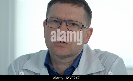 Männlicher Arzt in Gläsern im Gespräch mit der Kamera Stockfoto
