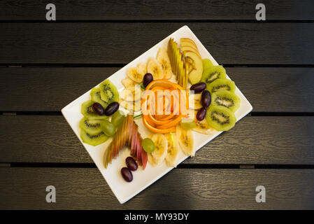 Obst schneiden in eine weiße Platte ist auf einem hölzernen Tisch Stockfoto