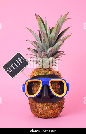 Nahaufnahme einer Ananas trägt einen blauen Tauchen Maske, und ein schwarzer Schild mit dem Text Sommer geschrieben, auf einem rosa Hintergrund Stockfoto
