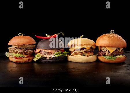 Satz von Burger mit Fleisch, Käse, Tomaten, Mayonnaise auf Holztisch, schwarzen Hintergrund. Platz für Text. Stockfoto