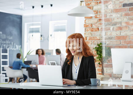 Happy Geschäftsfrau Arbeiten in modernen Büros mit Laptop Stockfoto